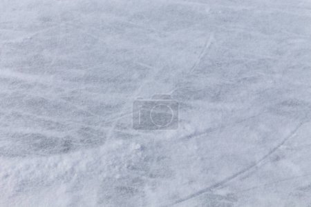Eishintergrund mit Spuren von Eislaufen und Hockey, blaue Struktur der Eisfläche mit vielen Kratzern