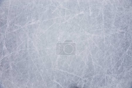 "Ice background with marks from skating and hockey, blue texture of rink surface with many scratches"