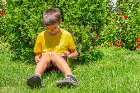 Foto de "Preadolescente chico lectura ebook en un gren hierba
" - Imagen libre de derechos