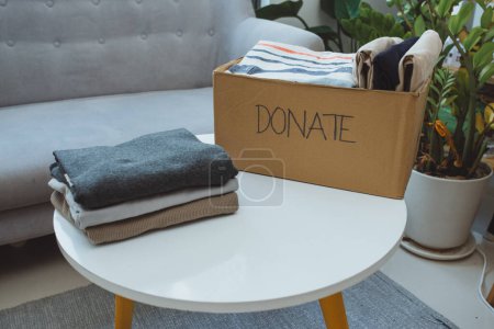Téléchargez les photos : "Boîte de don et vêtements décontractés dans le salon
" - en image libre de droit