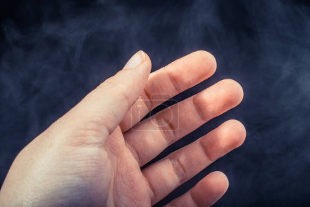 Téléchargez les photos : Main faisant un geste sur fond noir fumé - en image libre de droit