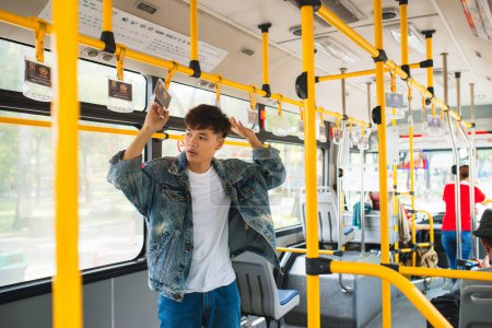 Foto de Asiático hombre tomando público transporte, de pie dentro de autobús
. - Imagen libre de derechos