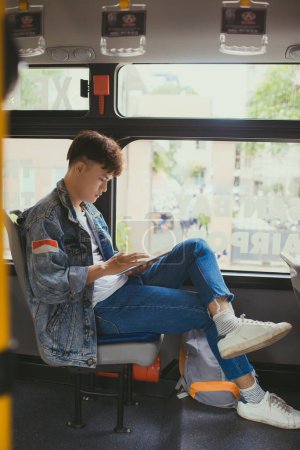 Téléchargez les photos : Beau jeune homme voyageant en bus et utilisant une tablette numérique - en image libre de droit