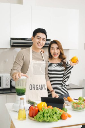 Foto de Feliz asiático pareja en amor en cocina haciendo saludable jugo - Imagen libre de derechos