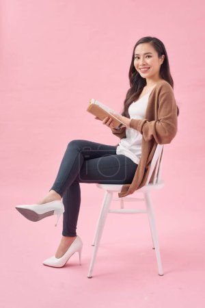 Foto de Hermosa chica con libro relajante en la silla - Imagen libre de derechos
