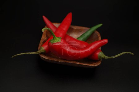 Photo for "Chili peppers on wooden over a black background" - Royalty Free Image