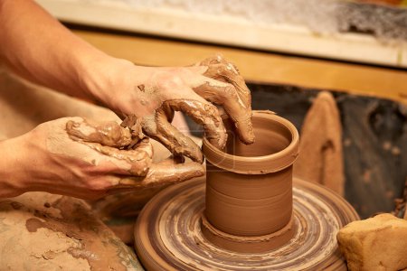 Foto de "Manos de hombre haciendo macro jarra de arcilla. El escultor del taller hace una jarra de loza de primer plano." - Imagen libre de derechos