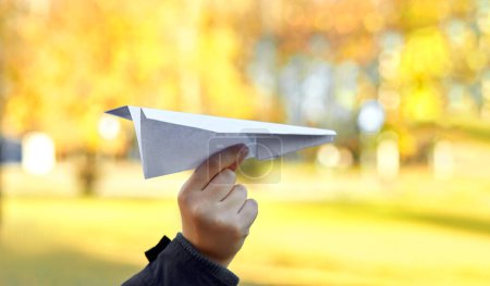 "Paper airplane in the hands of children on yellow backgr sunny day"