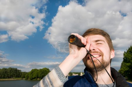 Photo for Handsome young man in casual clothes with binoculars on the background of a summer city - Royalty Free Image