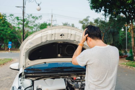 Foto de "joven estresado hombre que tiene problemas con su coche roto mirando en la frustración en el motor fallido" - Imagen libre de derechos