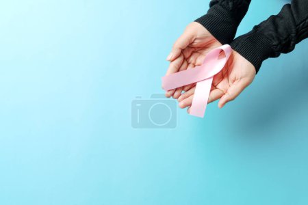 Foto de "cinta rosa de la insignia en la mano de la mujer para apoyar la causa del cáncer de mama. concepto de conciencia del cáncer de mama" - Imagen libre de derechos