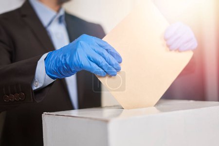 Téléchargez les photos : Une personne portant des gants médicaux votant - en image libre de droit
