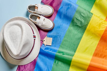 Téléchargez les photos : "Chapeau de voyage, chaussures d'été et clés de la maison sur drapeau arc-en-ciel" - en image libre de droit