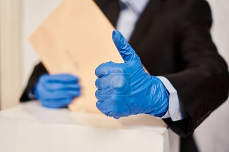 Téléchargez les photos : "Une personne portant des gants médicaux votant" - en image libre de droit