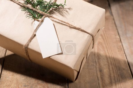 Photo for "Kraft paper box and green leaves on woodean background." - Royalty Free Image