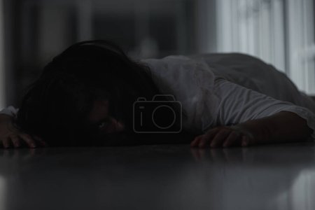 Téléchargez les photos : "Horror evil woman ghost creepy lying dead in a dark room at house" - en image libre de droit