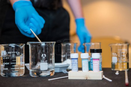Foto de "Látex mano enguantada verter un vaso de agua durante un experimento científico en el laboratorio de la escuela." - Imagen libre de derechos