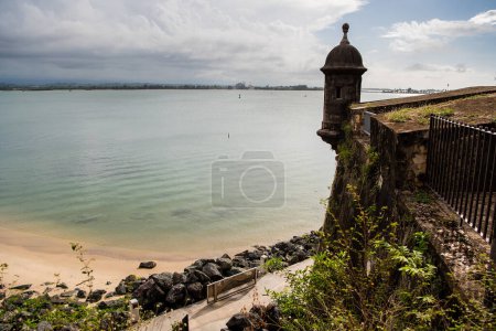 Téléchargez les photos : "Vue sur la plage et la tour du château à San Juan, Porto Rico avec des eaux claires et une plage rocheuse." - en image libre de droit