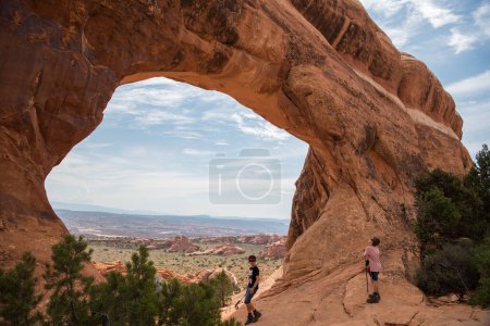 Téléchargez les photos : Arches National Park fenêtre arche scène avec gars et fille se promener - en image libre de droit
