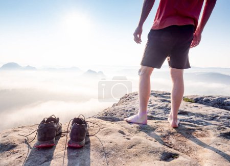 Téléchargez les photos : Corps masculin sain du moyen âge avec des jambes nues sur un rocher de montagne - en image libre de droit