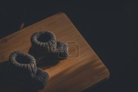Photo for A pair of gray booties for a small child. Early morning, light from the window. - Royalty Free Image