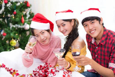 Téléchargez les photos : Groupe de jeunes asiatiques célébrant la fête du Nouvel An à la maison avec des verres à vin. Nouvel an et concept de fête de Noël. Concept de bonheur et d'amitié. Relation et drôle ensemble thème. - en image libre de droit