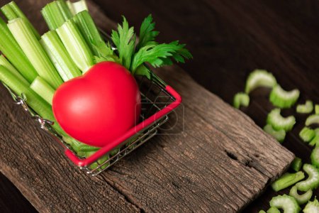Photo for Bunch of fresh celery stalk in shopping basket with leaves and red heart for healthy concept. Food and ingredients of vegetable. Freshness herbal and low calories for dieting with plenty of vitamin - Royalty Free Image
