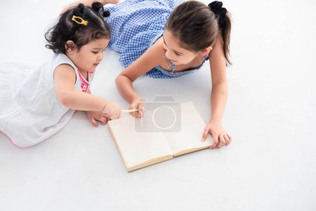 Photo for Top view of happy two sister drawing in sketch book together at home or nursery. People lifestyle and kids play. Education and Children concept. Diverse ethnicity and ages. Back to school theme - Royalty Free Image