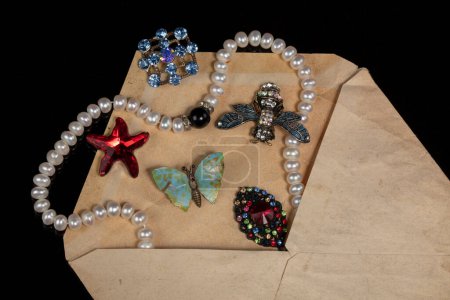 Photo for Jewelry, brooches, beads were poured out of an old mail envelope. - Royalty Free Image