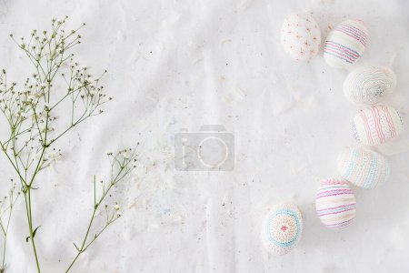 Téléchargez les photos : "rangée d'oeufs de Pâques avec des motifs près de plantes plumes de rameaux textile. Photo de haute qualité" - en image libre de droit