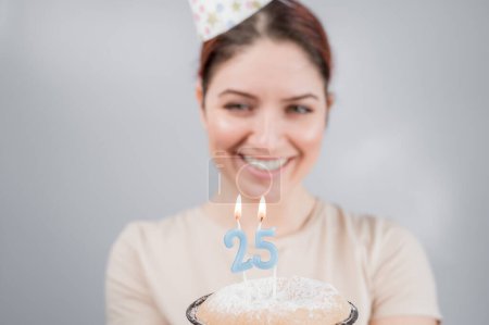 Foto de La mujer feliz pide un deseo y sopla las velas en el pastel de cumpleaños 25. Chica celebrando cumpleaños. - Imagen libre de derechos