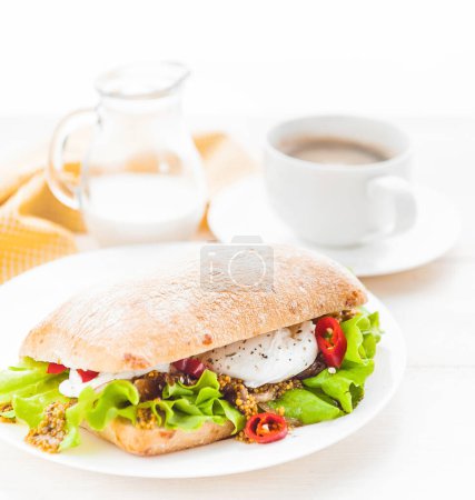 Téléchargez les photos : "breakfast in a rustic style on a white wooden surface. ciabatta with poached egg and grain mustard with a hot cup of coffee and fresh" - en image libre de droit