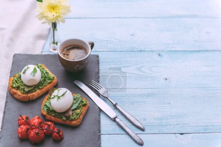 Photo for "Breakfast with egg poached on avocado paddle and basil and a cup of coffee" - Royalty Free Image
