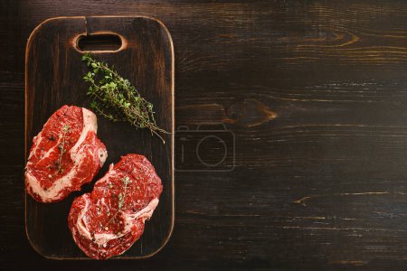 Photo for "two raw marbled beef steaks in olive oil and spices ready for frying. dinner party concept" - Royalty Free Image