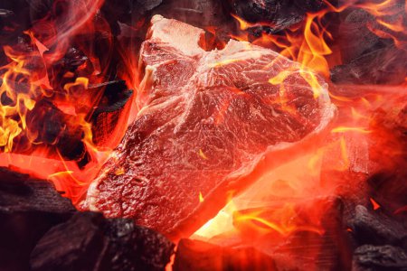 Foto de "raw marbled beef steak with coals and smoke" - Imagen libre de derechos