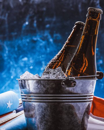 Photo for "two bottles of beer in an ice bucket with the American flag lying nearby and rockets for fireworks. Independence Day celebration concept" - Royalty Free Image
