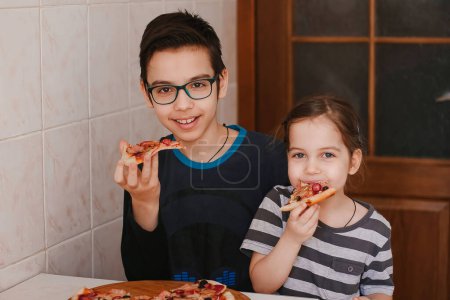 Photo for "Happy children boy and girl eating pizza at home" - Royalty Free Image