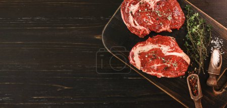 Photo for "two raw marbled beef steaks in olive oil and spices ready for frying. dinner party concept" - Royalty Free Image