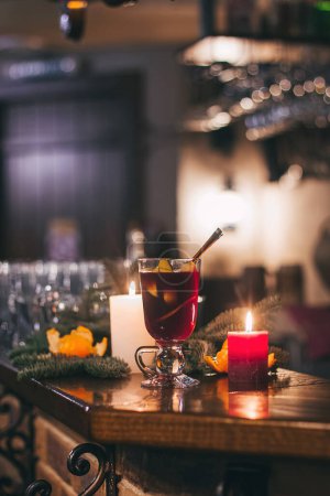 Foto de Bebida caliente roja glintwein con especias, canela, anís, frutas, azúcar morena en una vieja mesa de madera. Concepto de Año Nuevo y Navidad. Vino caliente y glintwein - Imagen libre de derechos