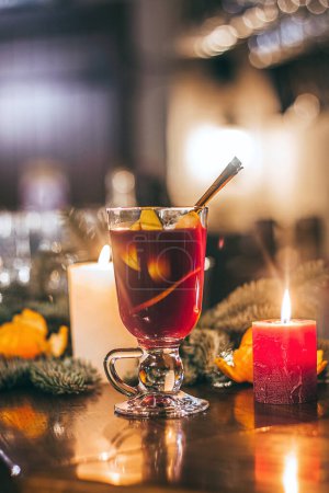 Foto de Bebida caliente roja glintwein con especias, canela, anís, frutas, azúcar morena en una vieja mesa de madera. Concepto de Año Nuevo y Navidad. Vino caliente y glintwein - Imagen libre de derechos