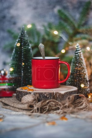 Photo for Cozy winter drink hot chocolate cocoa in red mug with fir tree, candles and Christmas lights. - Royalty Free Image