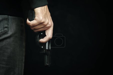 Man in dark clothing is holding gun.