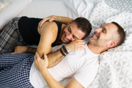 Photo for "Gay couple hugging together on their bed." - Royalty Free Image