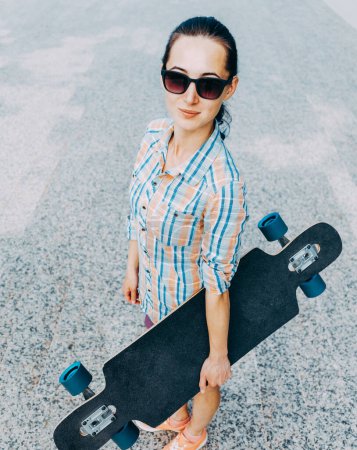 Photo for Stylish girl with longboard, looking at camera - Royalty Free Image