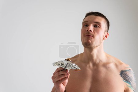Photo for Man eats protein bar on white background isolated protein energy food, holding athlete caucasian, delicious calorie. break granola, smile female - Royalty Free Image