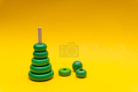 Photo for Pyramid build from green children wooden toy rings at yellow background. - Royalty Free Image