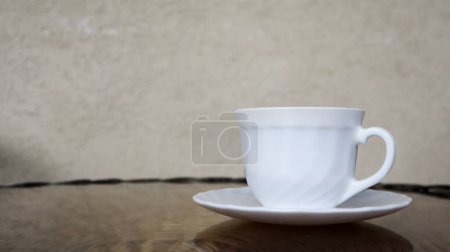 Foto de Café aromático caliente con leche. Bebida recién preparada se sirve en una taza moderna en una mesa de mimbre ligera. - Imagen libre de derechos