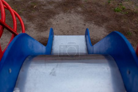 Téléchargez les photos : Toboggan pour enfants avec des côtés bleus et une surface métallique brillante. Vue du haut vers le bas de la glissière pour enfants - en image libre de droit