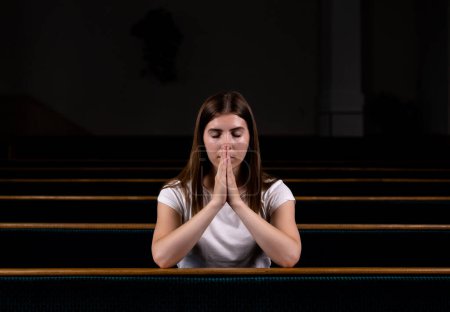 Téléchargez les photos : Fille chrétienne en chemise blanche est assis et priant avec un cœur humble dans l'église - en image libre de droit
