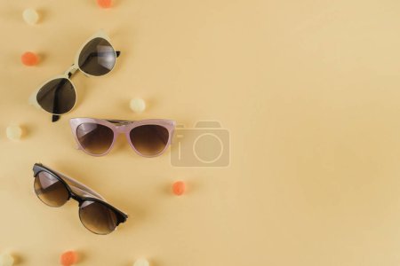 Foto de Diferentes tipos de gafas de sol con pompones fondo beige - Imagen libre de derechos
